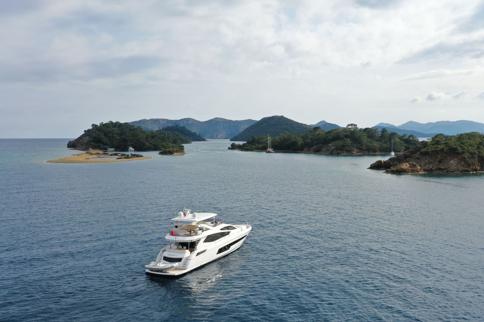 A motor yacht at anchor among the pine-covered islands of Göcek, seen from the air